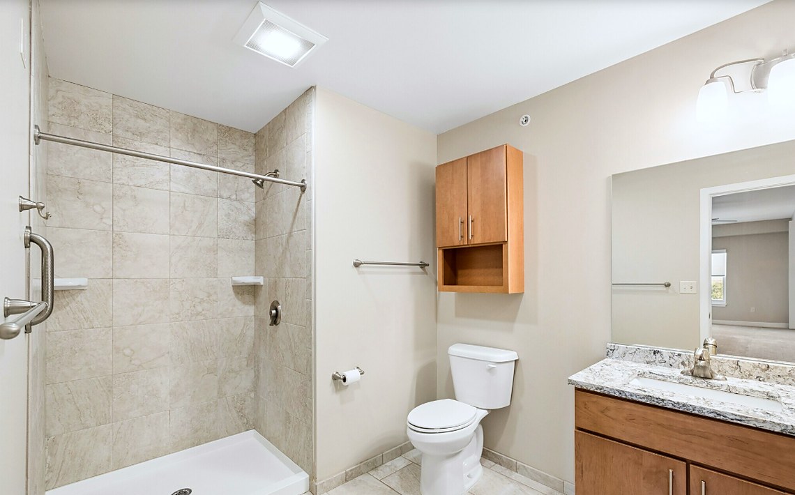 An accessible bathroom at Charlotte Square with a roll-in shower and grab bars